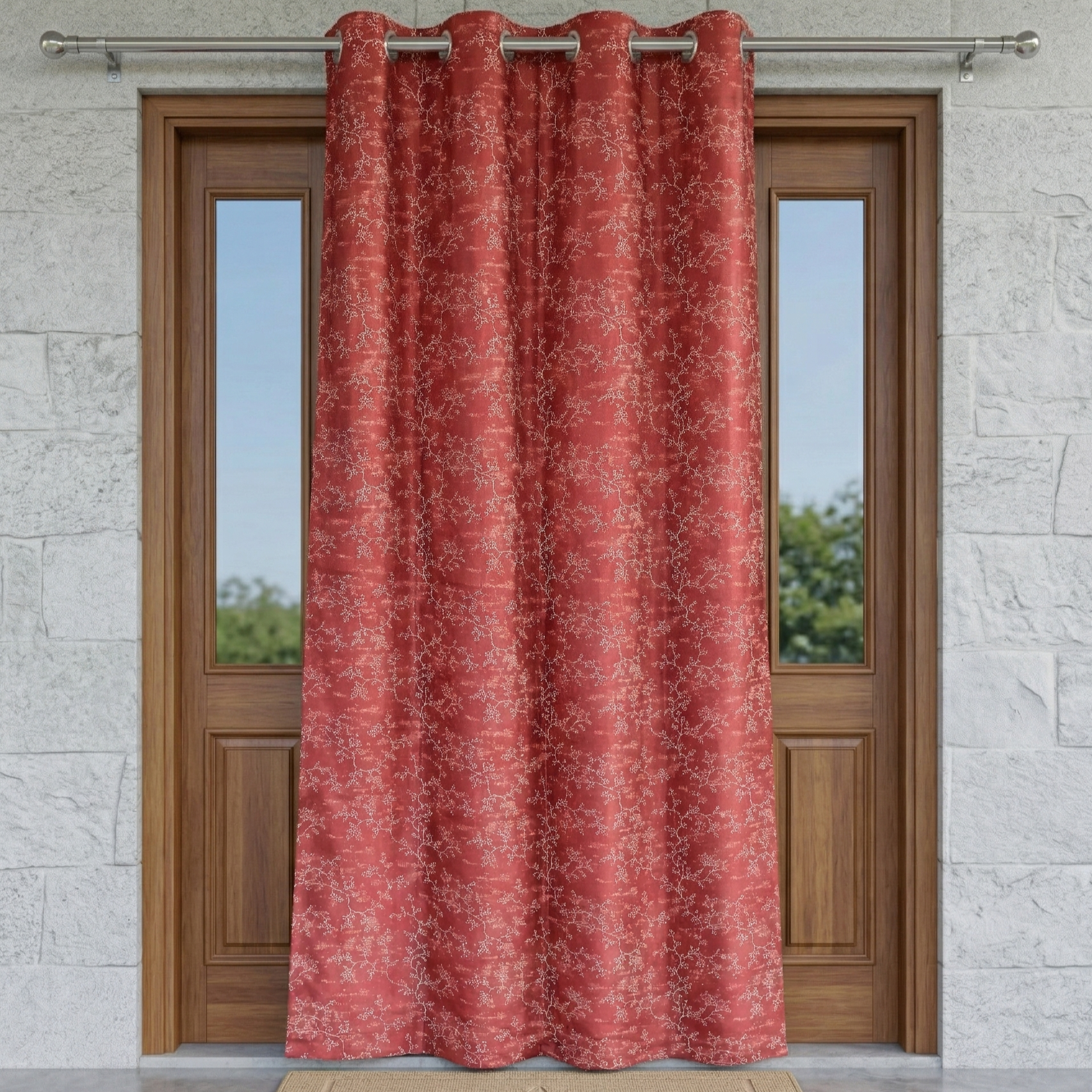 Red floral patterned curtain hanging in front of a wooden door with stone wall background